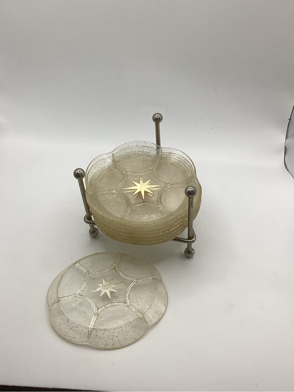 vintage MCM 1960s drink coasters with a starburst design and a chrome holder
